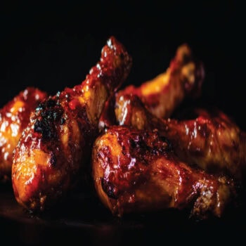 A basket of crispy, juicy chicken wings heavily coated in a sticky, glistening sweet and smoky honey BBQ sauce, served fresh at Let's Fry Away.
